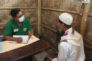 Refugee from Rohingya talking with MSF's medical assistant, Robiul Awal, in a healthcare setting.