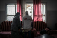 MSF staff with patient look out house window