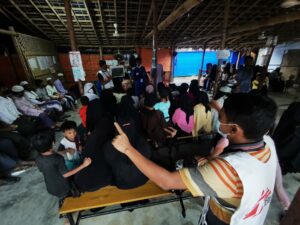 MSF community-based health promotion volunteers leading a session to a group of people inside a shade in Jamtoli Clinic, Ukhiya, Cox’s Bazar, Bangladesh.