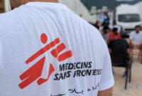 A man in white shirt with an MSF logo printed on the back.