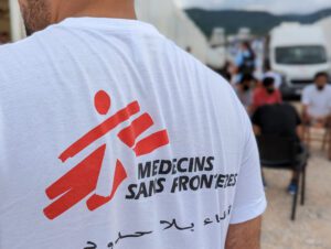 A man in white shirt with an MSF logo printed on the back.