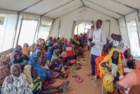 Refugees from Sudan await consultations with MSF nurses for nutritional support under a tent.
