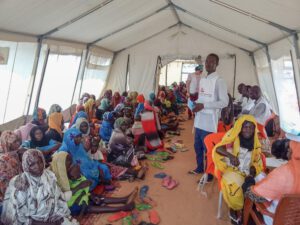 Refugees from Sudan await consultations with MSF nurses for nutritional support under a tent.
