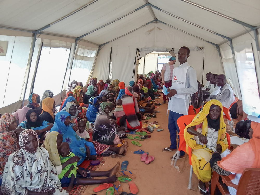 Refugees from Sudan await consultations with MSF nurses for nutritional support under a tent.