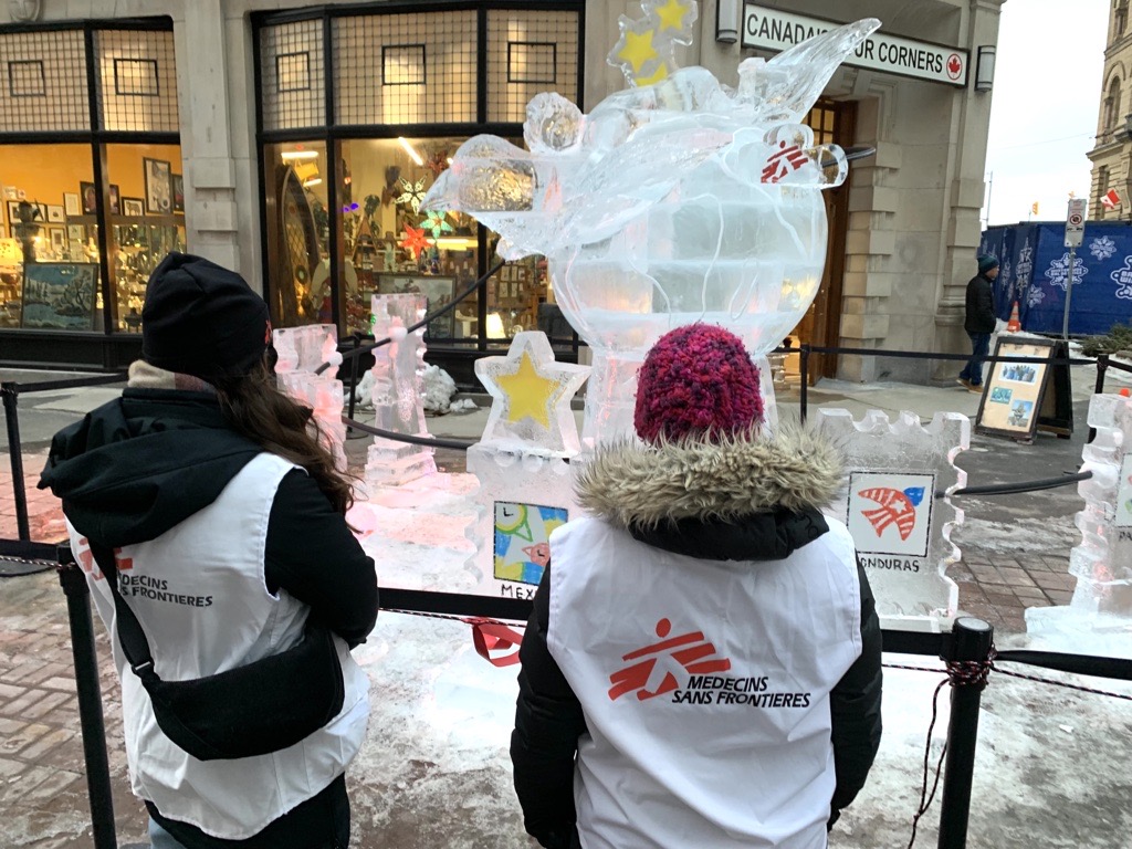 Two MSF staff looking at the Little Birds ice sculpture at Winterlude Ottawa 2024. 