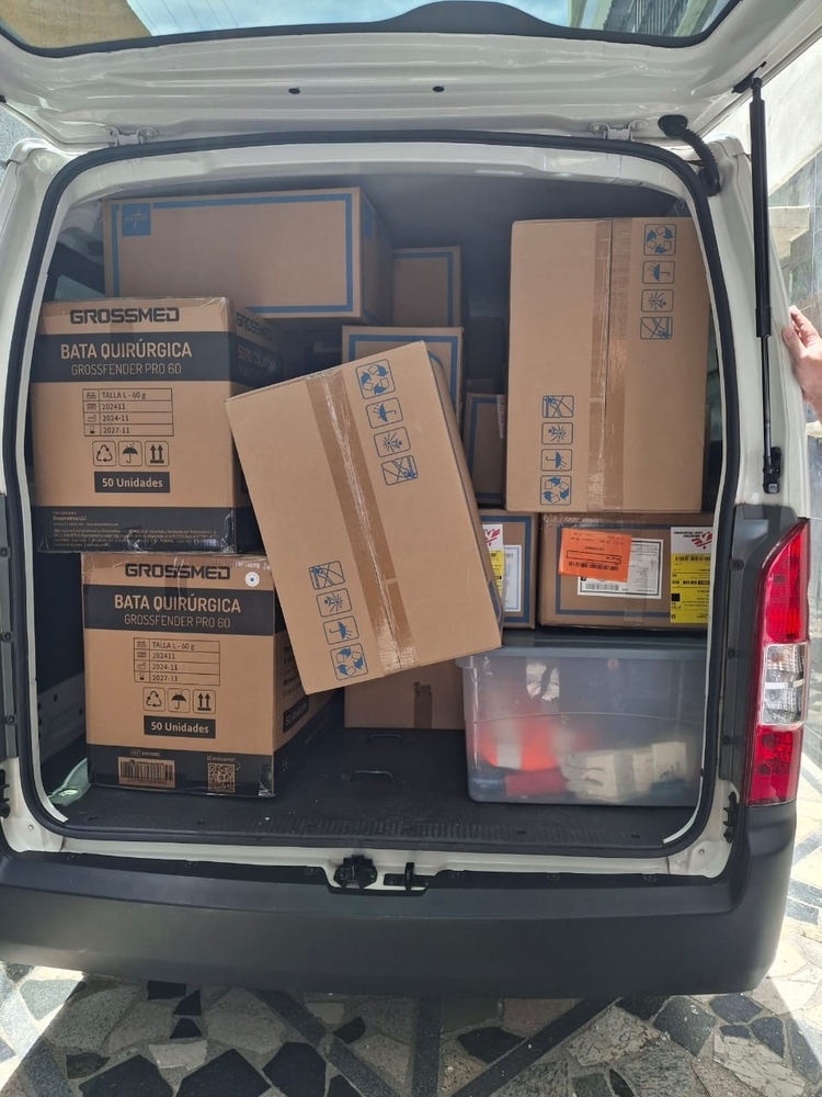 A van with its doors open and loaded with boxes full of supplies.